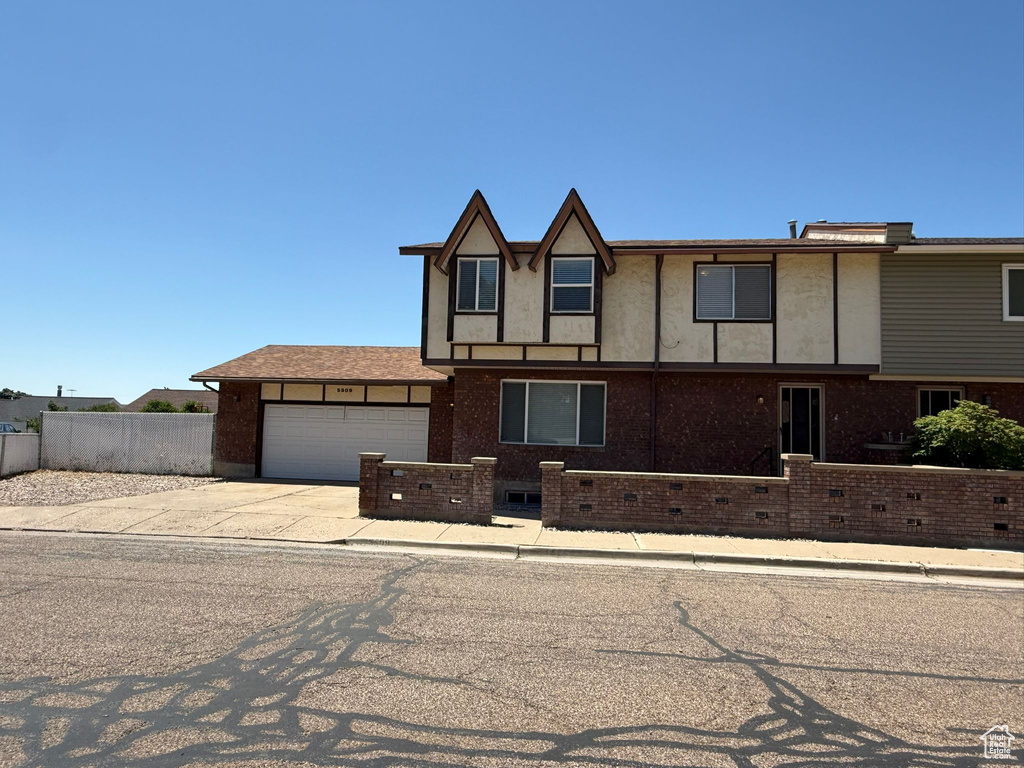 View of front of house featuring an attached garage, concrete driveway, and brick siding
