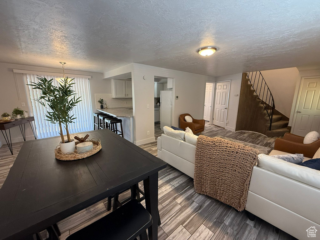Living area featuring a textured ceiling, stairs, baseboards, and wood finished floors