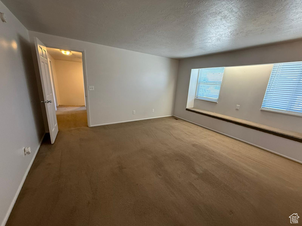 Unfurnished room with carpet flooring, baseboards, and a textured ceiling