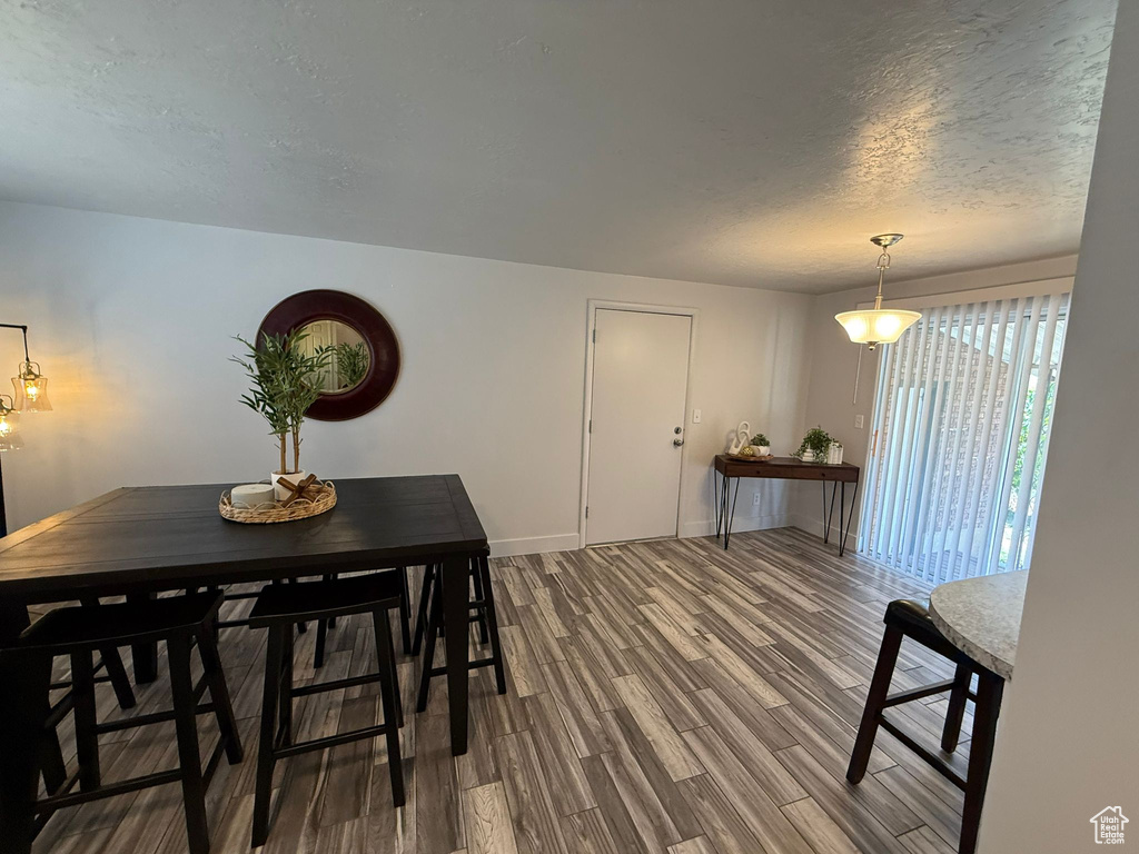 Dining space featuring dark wood-style floors, a textured ceiling, and baseboards