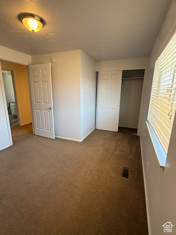 Unfurnished bedroom featuring carpet, baseboards, a closet, and a textured ceiling
