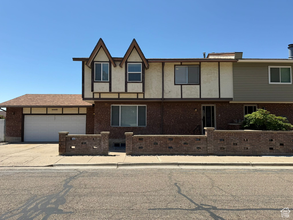 View of front of property featuring an attached garage, driveway, and brick siding