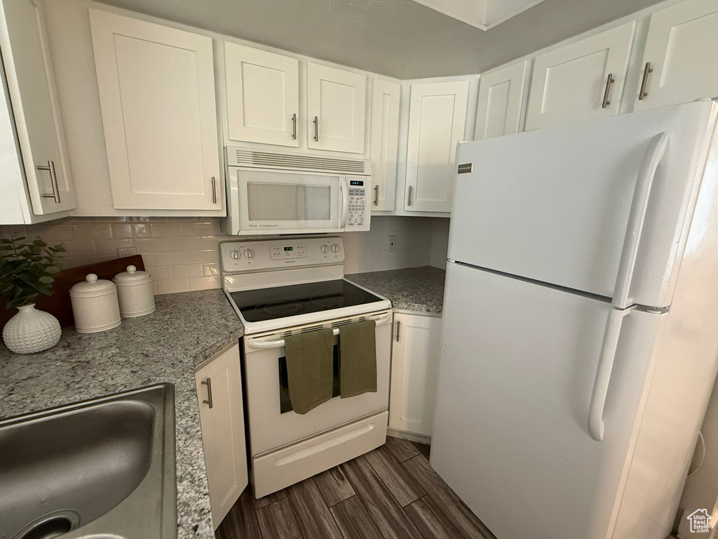Kitchen with white appliances, dark wood-style floors, white cabinets, a sink, and decorative backsplash