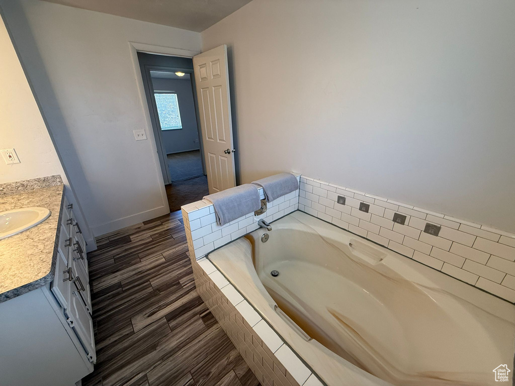 Bathroom with vanity, a bath, wood finished floors, and baseboards