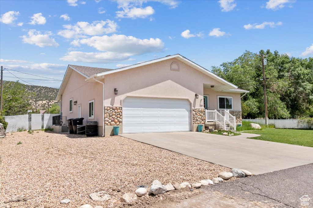 View of front of home with stucco siding, stone siding, an attached garage, and concrete driveway