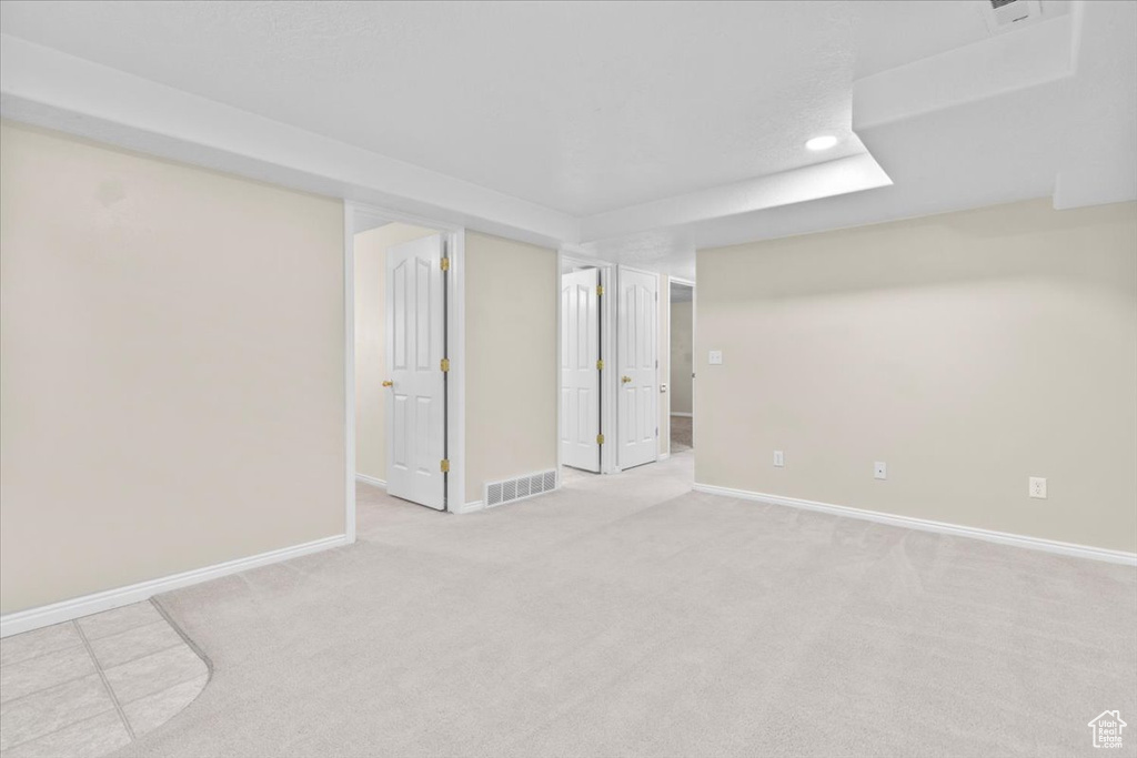 Empty room with light colored carpet and recessed lighting