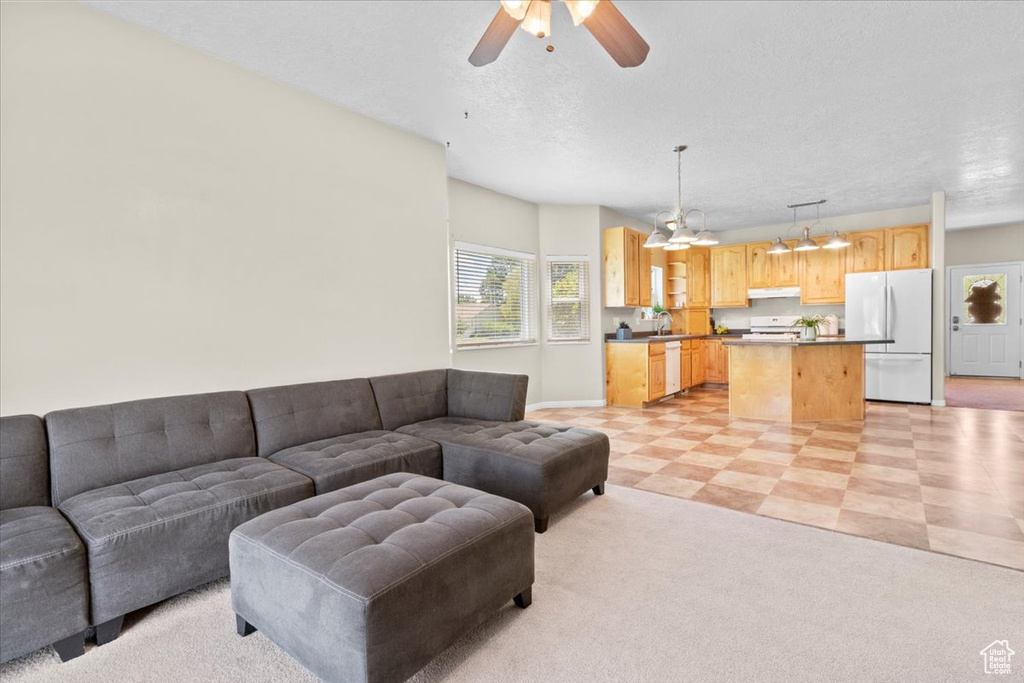 Living room with ceiling fan, a textured ceiling, and a chandelier