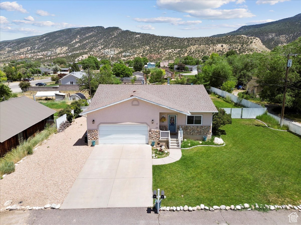 View of front of property with stone siding, driveway, a garage, and a mountain view