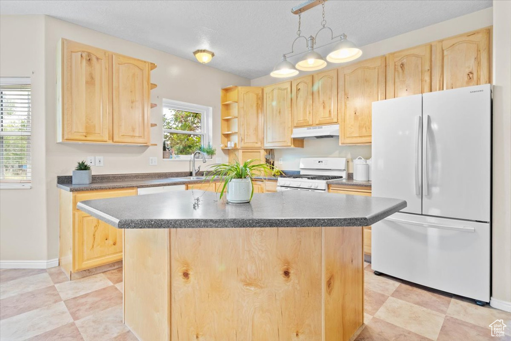 Kitchen with white appliances, light brown cabinetry, under cabinet range hood, open shelves, and dark countertops