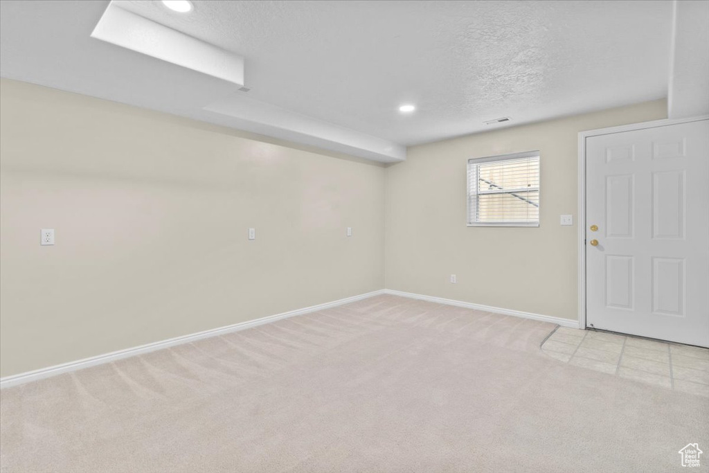 Below grade area with light colored carpet, a textured ceiling, and recessed lighting