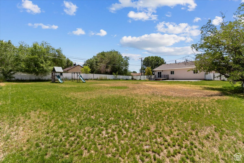 Fenced backyard featuring a playground