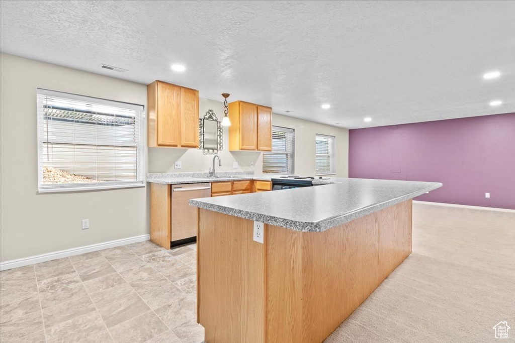 Kitchen featuring stainless steel dishwasher, recessed lighting, a textured ceiling, light brown cabinets, and light countertops