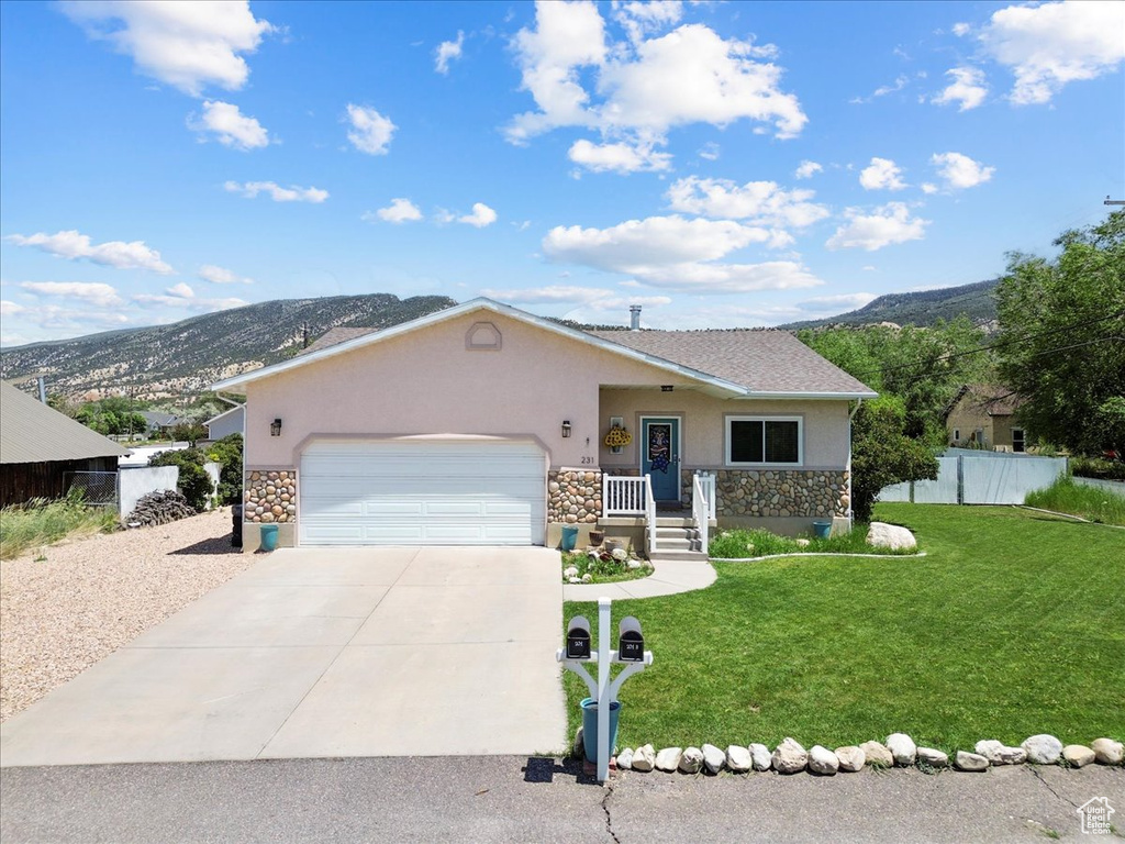 View of front of house featuring stone siding, stucco siding, a mountain view, and a garage