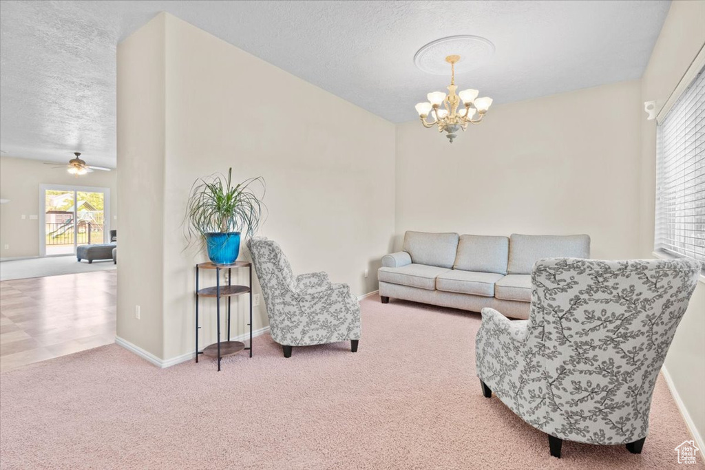Living room featuring carpet, a chandelier, plenty of natural light, a textured ceiling, and ceiling fan