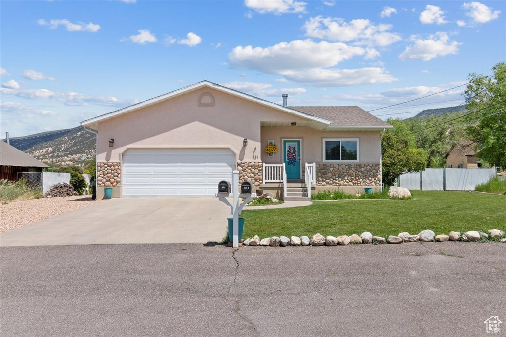 View of front of property with stucco siding, stone siding, an attached garage, driveway, and a mountain view