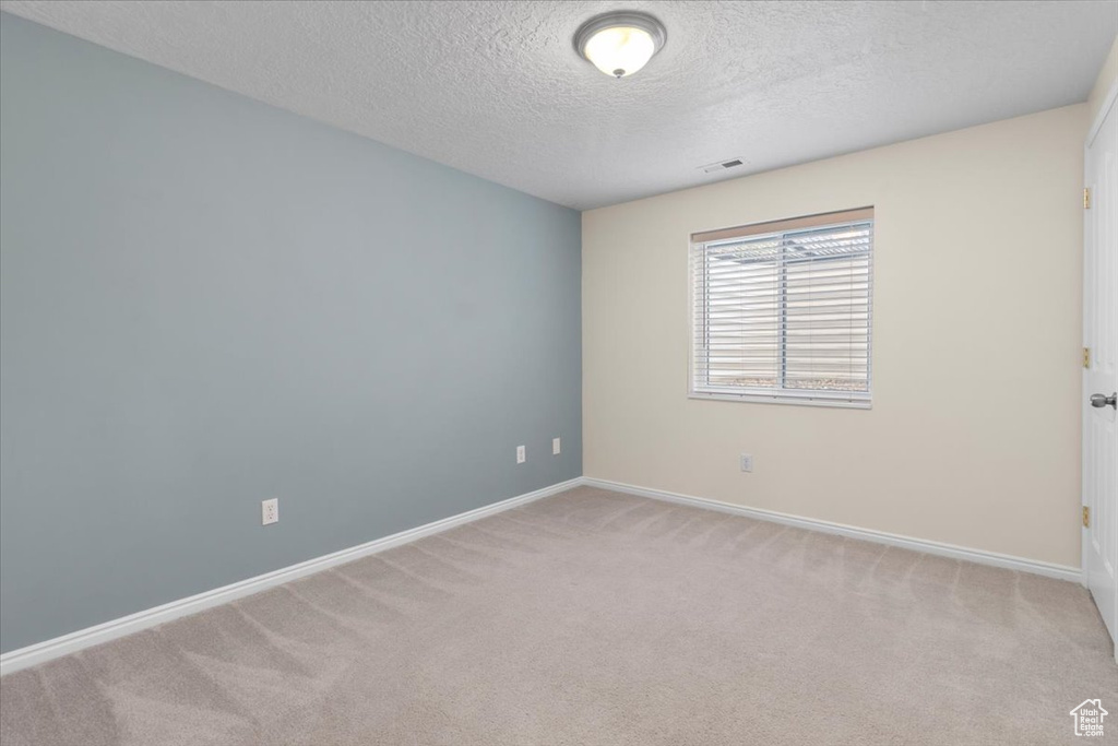 Carpeted empty room featuring baseboards and a textured ceiling