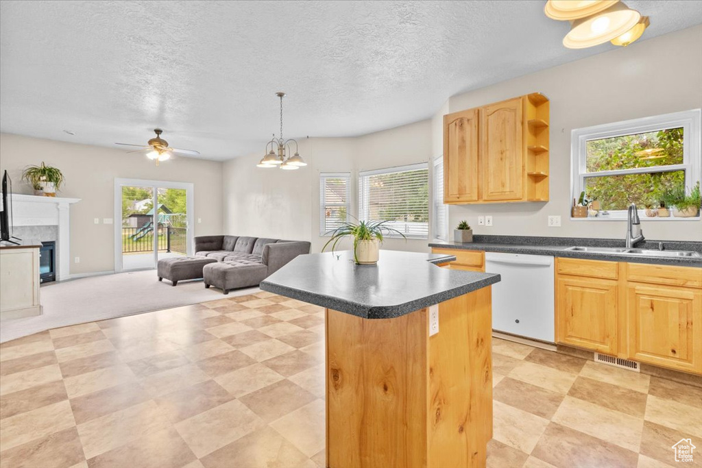 Kitchen with dishwasher, a center island, dark countertops, light brown cabinetry, and a fireplace