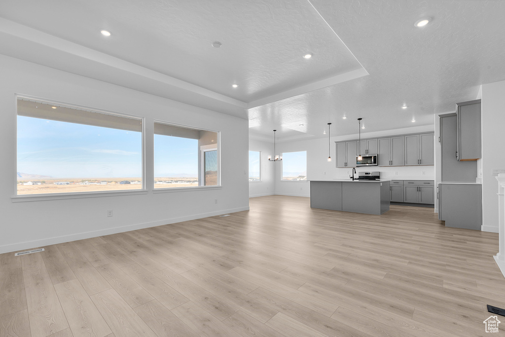 Unfurnished living room with a tray ceiling, recessed lighting, and light wood-style flooring