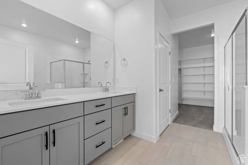Full bathroom with a shower stall, double vanity, a spacious closet, and recessed lighting