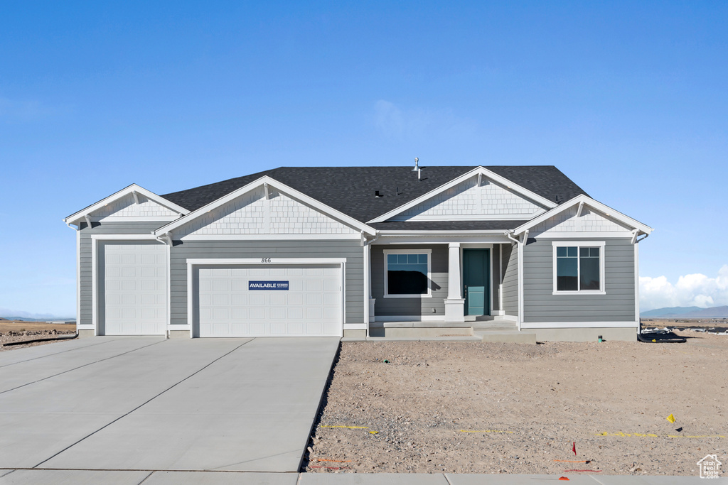 View of front of house featuring a garage, concrete driveway, and covered porch