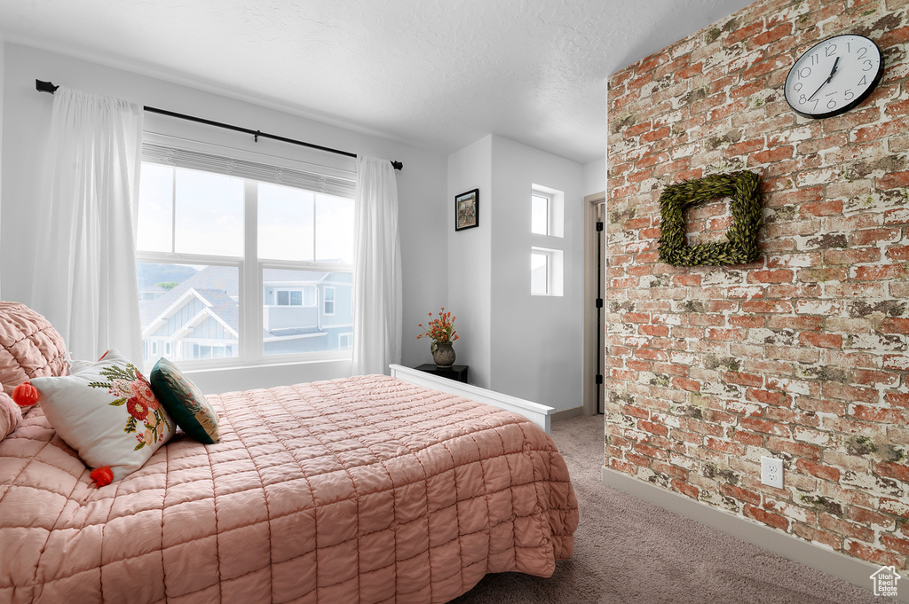 Bedroom featuring light colored carpet, multiple windows, and a textured ceiling