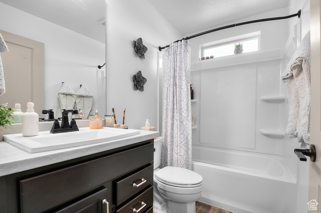 Full bath with vanity, shower / bath combo, and wood finished floors