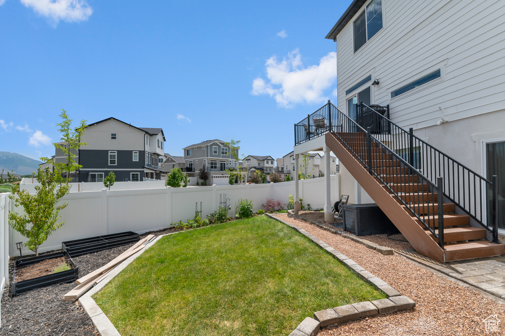 Fenced backyard featuring a residential view, stairway, and a garden