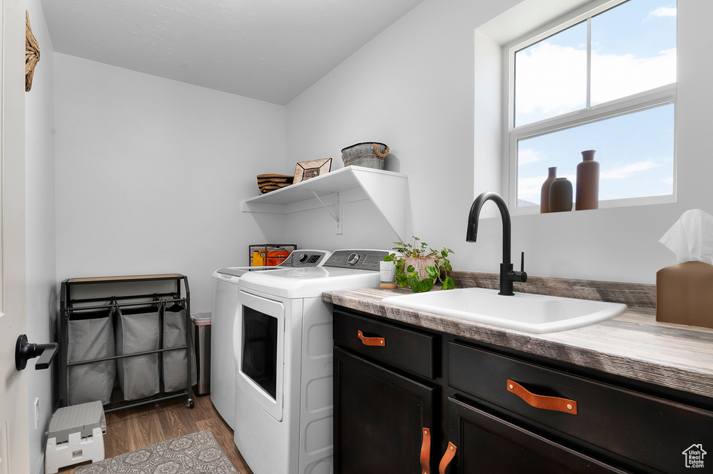 Laundry area with washer and dryer, cabinet space, and wood finished floors