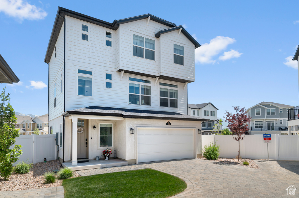View of front of home with a garage, driveway, a gate, and a residential view