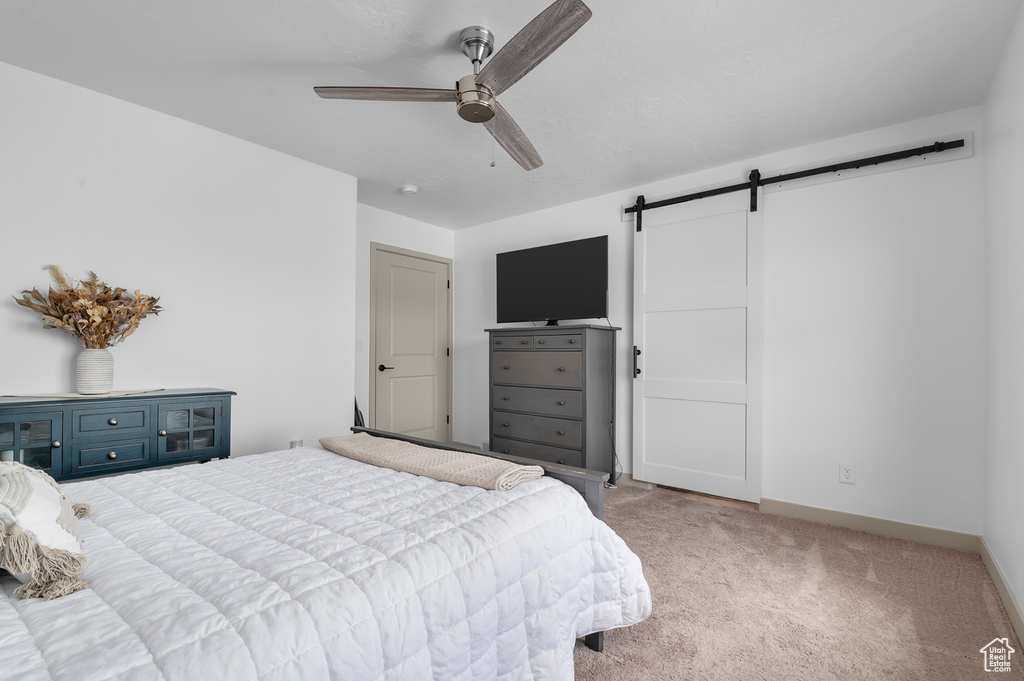 Bedroom featuring a barn door, carpet flooring, and ceiling fan