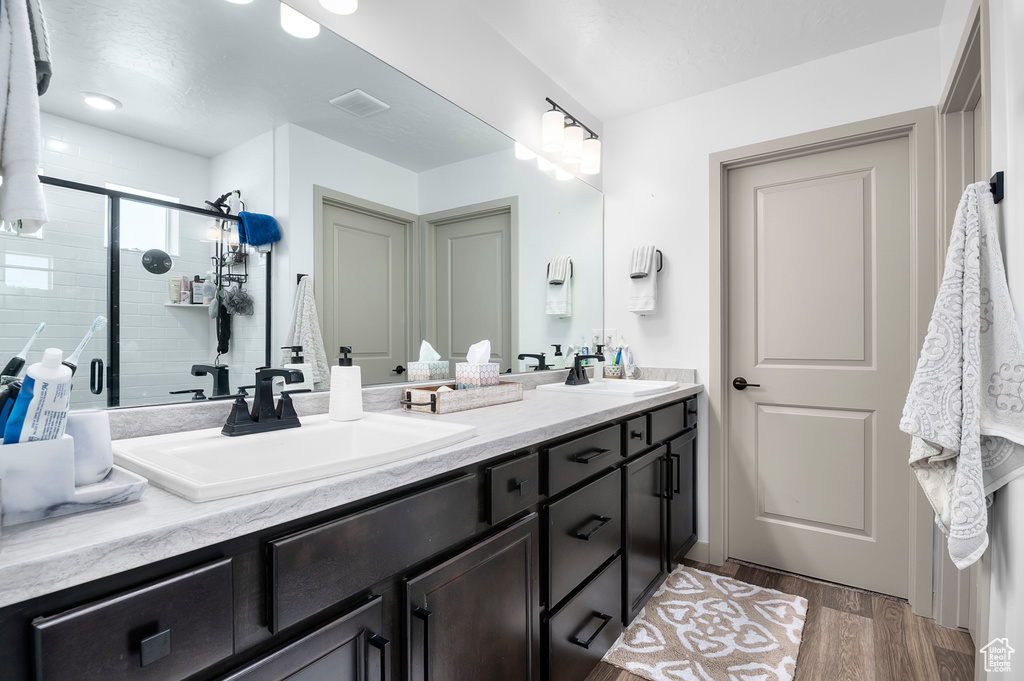 Full bathroom featuring double vanity, wood finished floors, and a shower stall