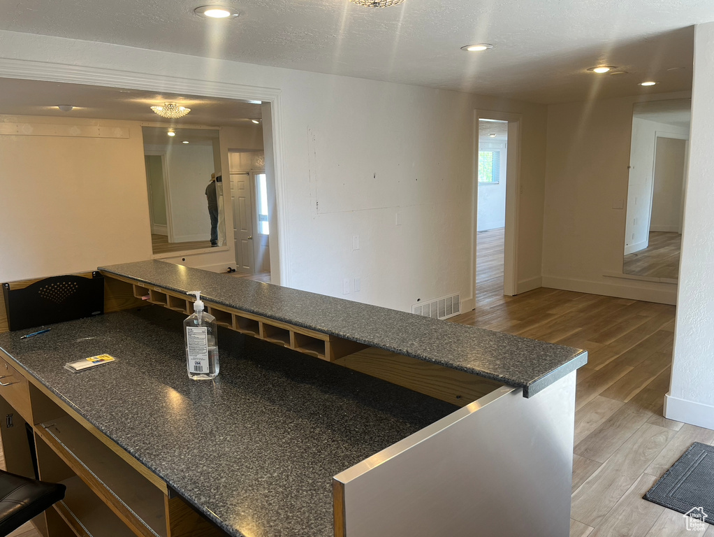 Kitchen featuring light wood finished floors, dark countertops, and recessed lighting