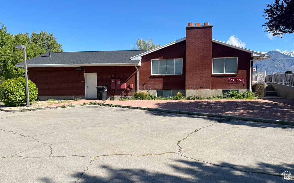 View of side of home with brick siding, a chimney, and uncovered parking