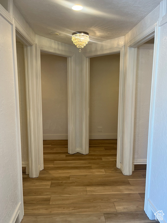 Hallway featuring wood finished floors and a chandelier