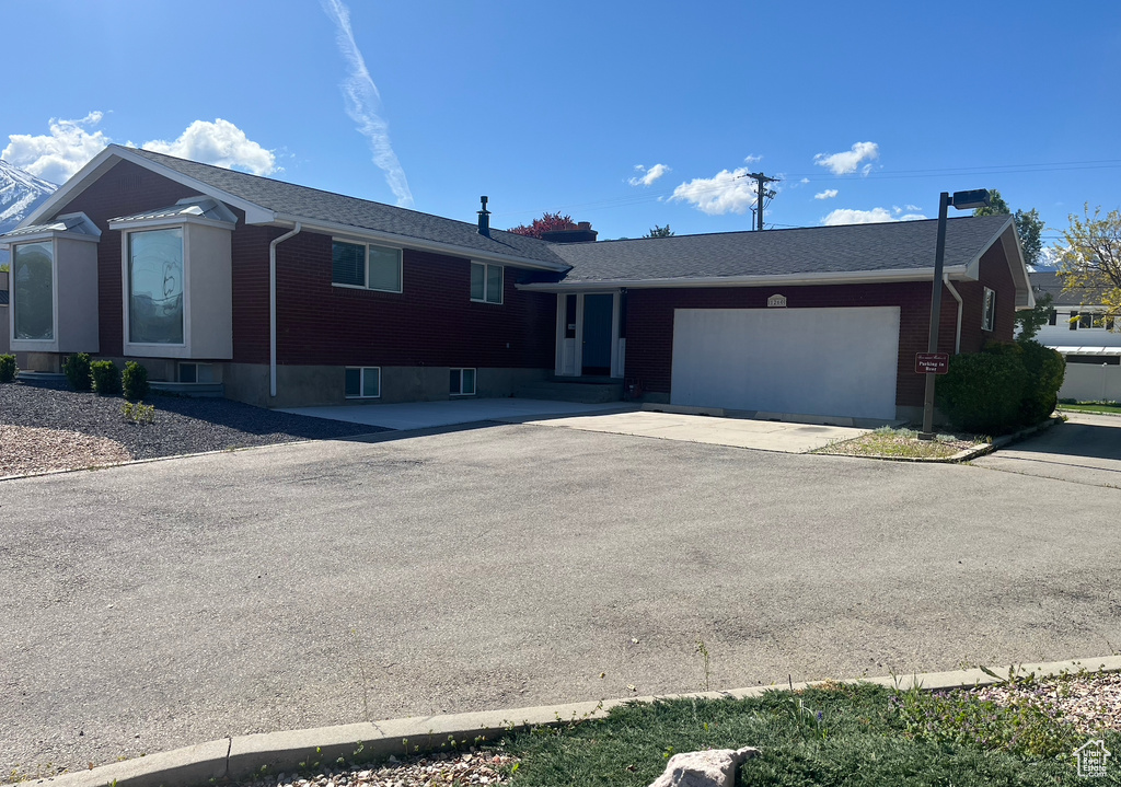 Single story home featuring an attached garage, driveway, and brick siding