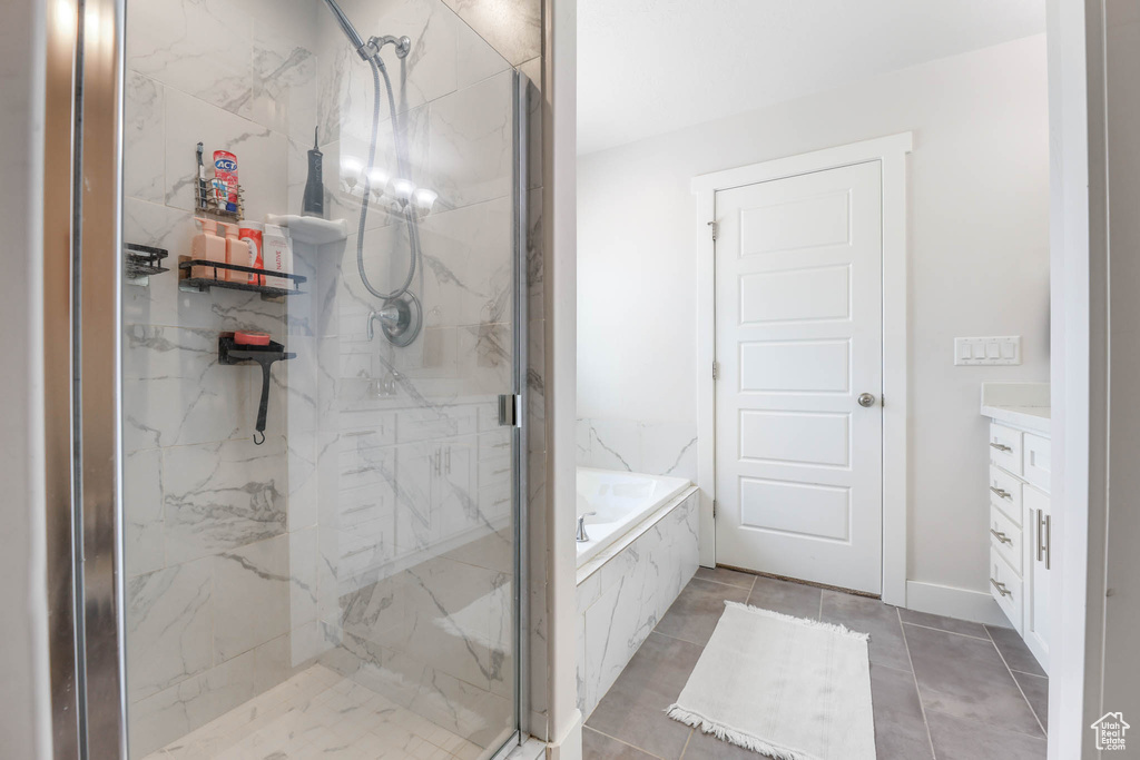 Bathroom featuring a bath, a marble finish shower, vanity, and tile patterned flooring