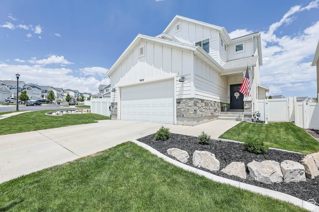 View of front of property featuring board and batten siding, a gate, driveway, stone siding, and a residential view