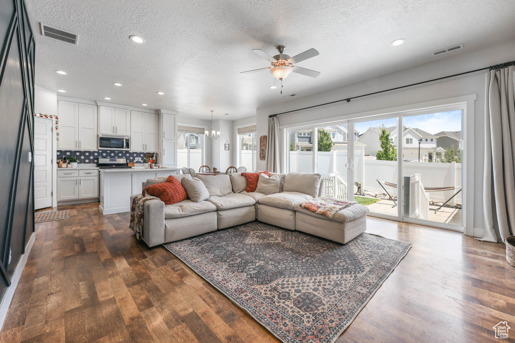 Living room with a textured ceiling, ceiling fan, dark wood finished floors, and recessed lighting