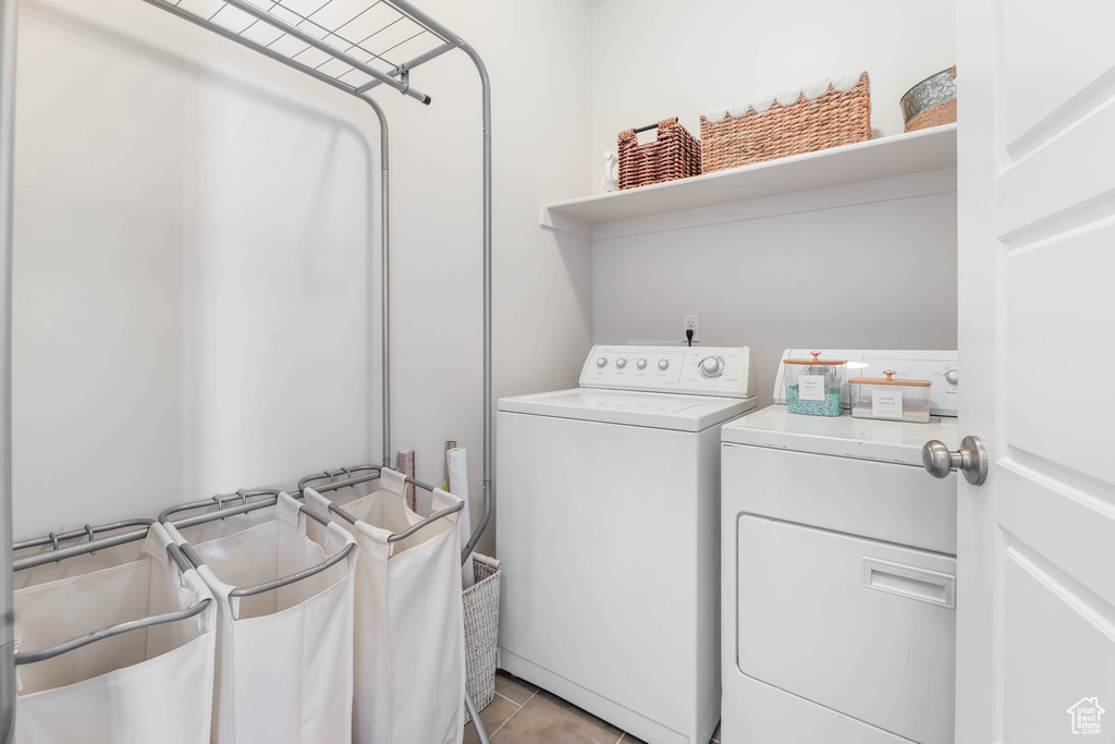 Laundry area with independent washer and dryer and light tile patterned floors