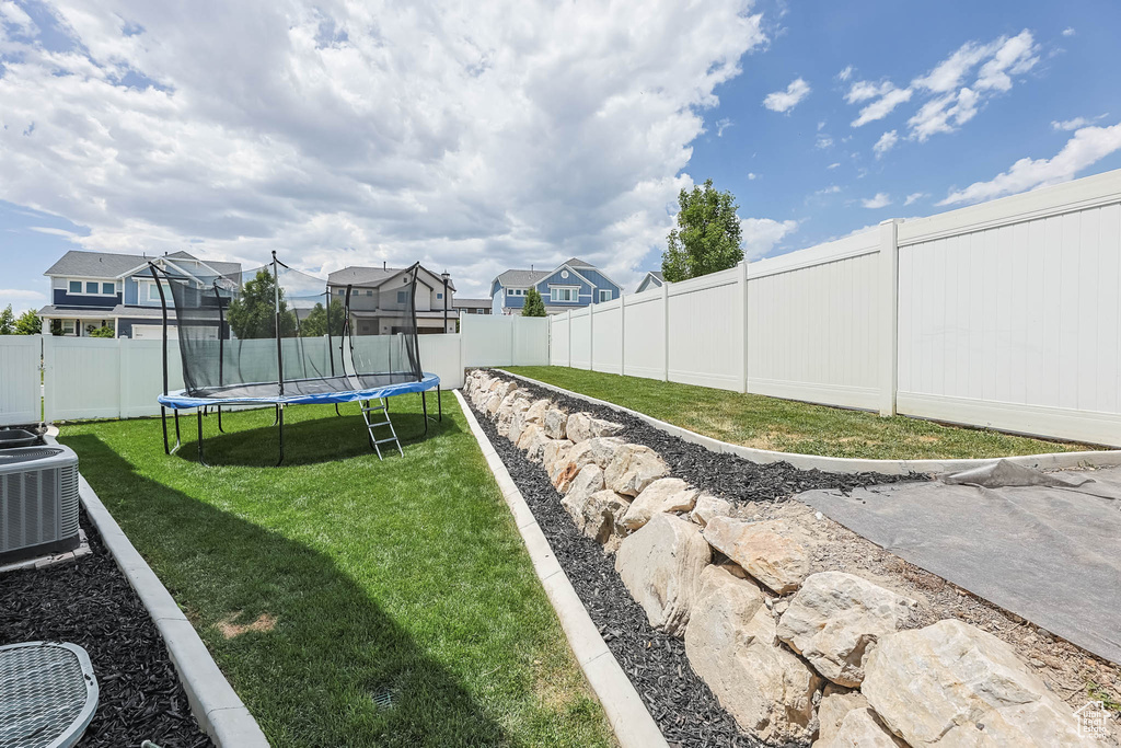 Fenced backyard featuring a trampoline and a residential view