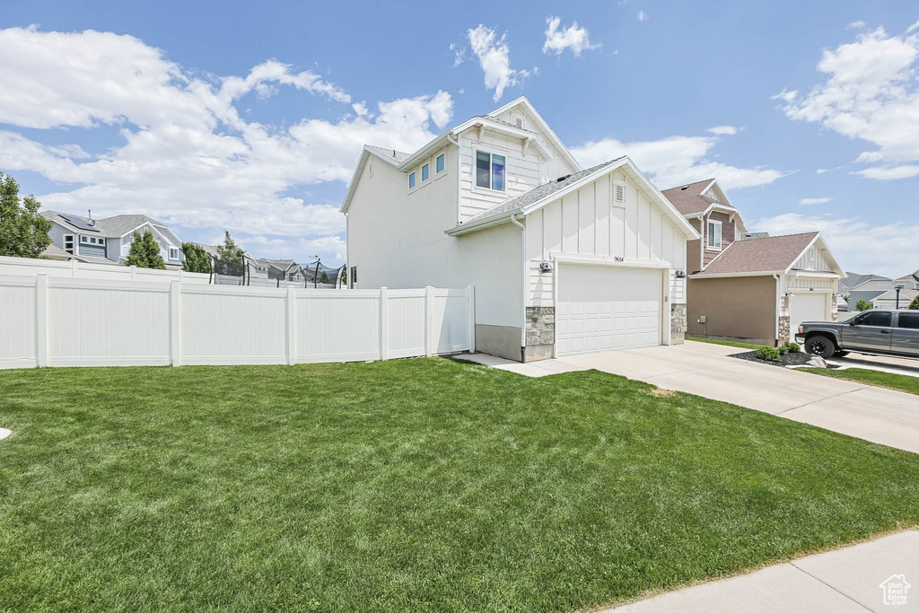 View of home\'s exterior with board and batten siding, concrete driveway, an attached garage, and a residential view