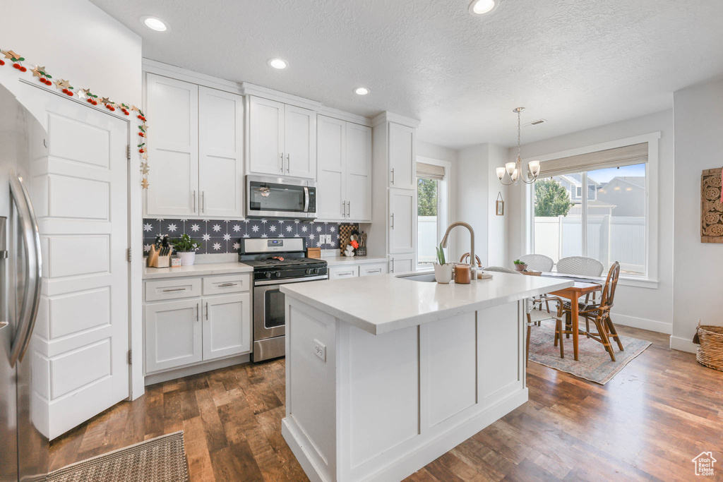 Kitchen with stainless steel appliances, white cabinetry, light countertops, recessed lighting, and a chandelier