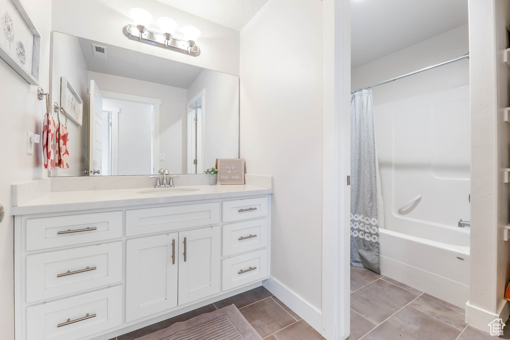 Full bath with vanity, shower / bath combo, and tile patterned flooring
