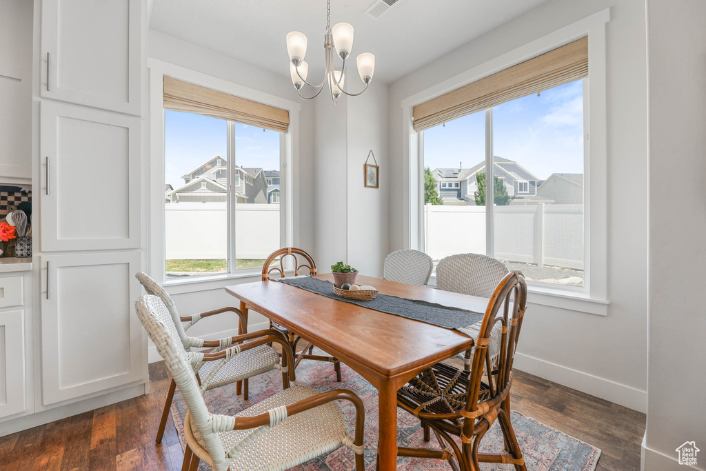 Dining space with healthy amount of natural light, dark wood-style flooring, and a chandelier