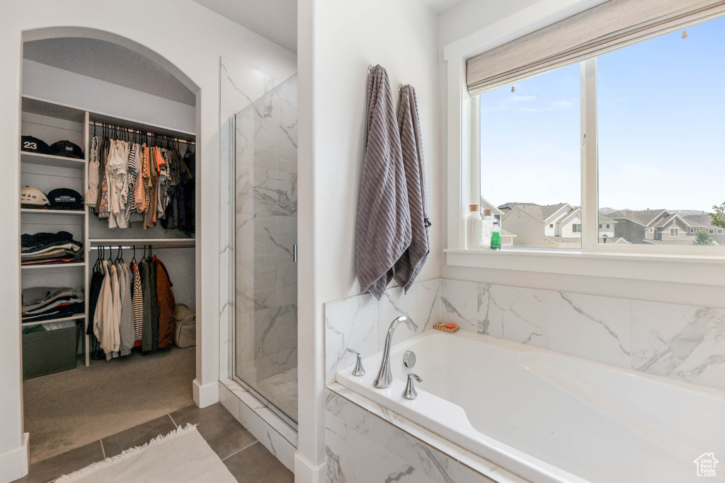Bathroom with a garden tub, a marble finish shower, plenty of natural light, and a walk in closet