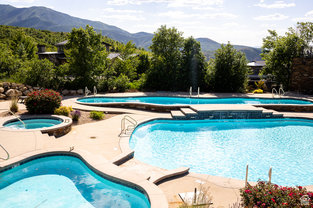 Community pool with a hot tub, a mountain view, and a patio