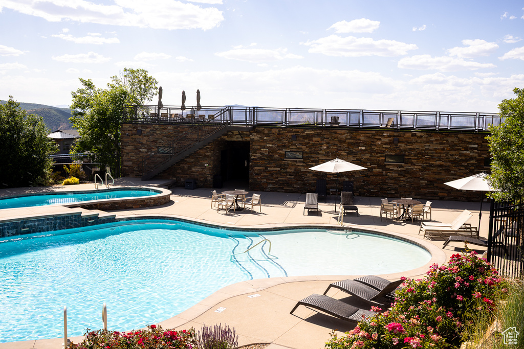 Community pool with a jacuzzi, a patio area, and stairway