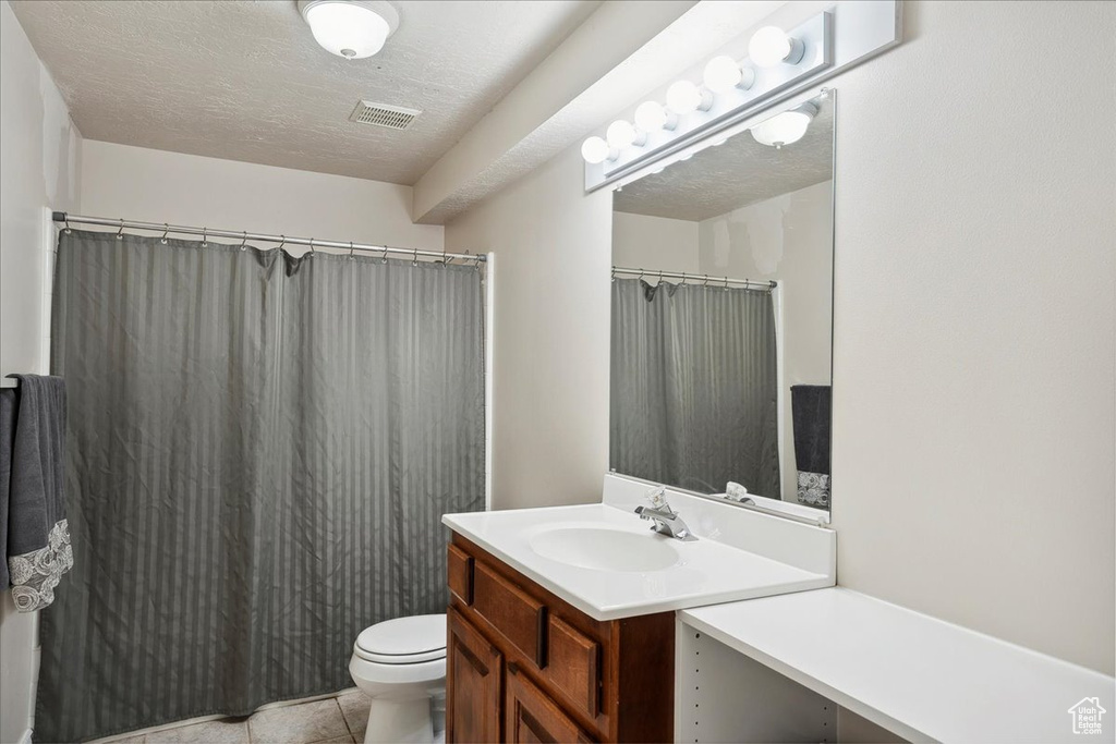 Full bath featuring vanity, a textured ceiling, curtained shower, and tile patterned floors