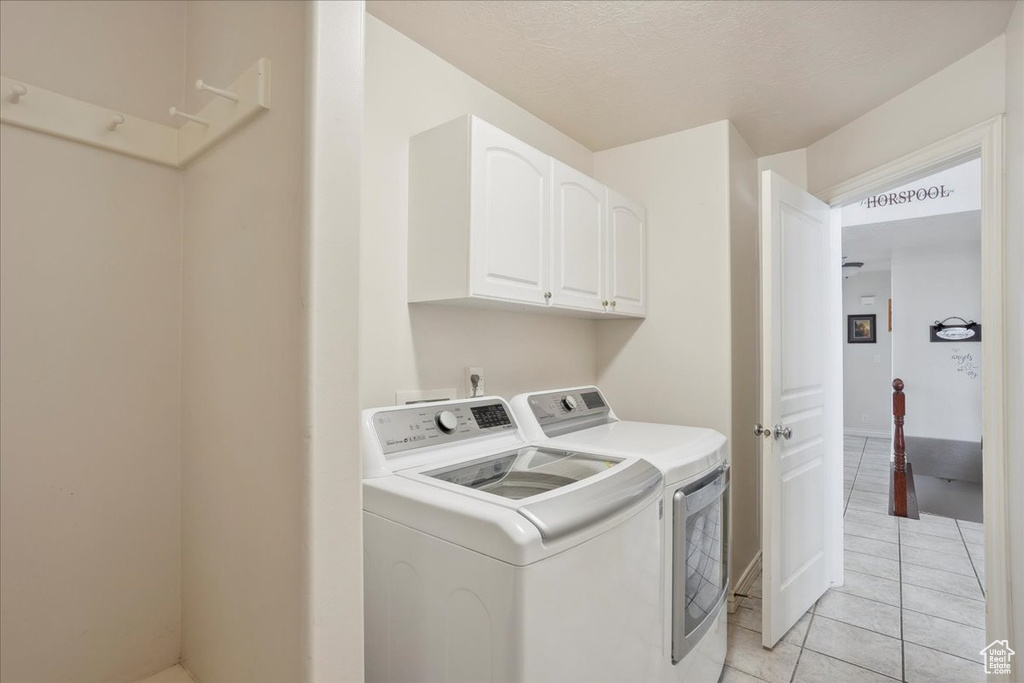 Washroom with washing machine and dryer, cabinet space, and light tile patterned floors