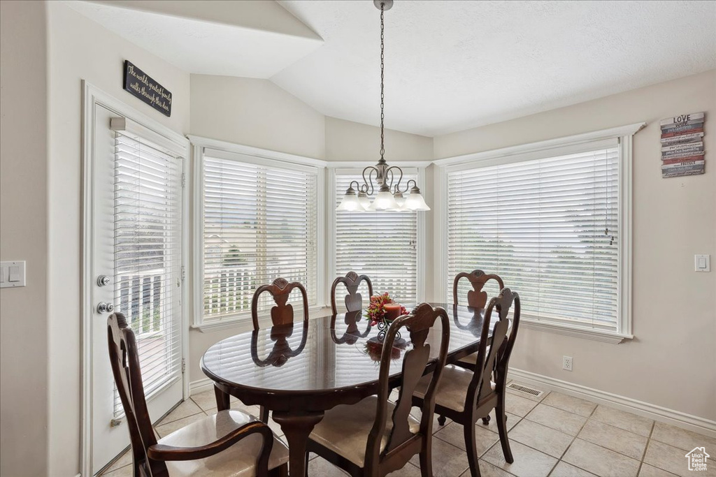 Dining room with vaulted ceiling, light tile patterned floors, and a chandelier